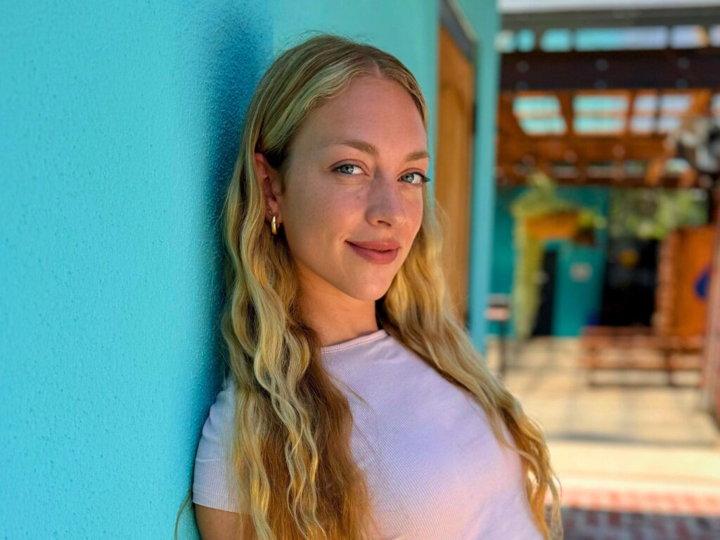 Sianne leaning against a bright blue wall in Austin